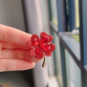 Detailed view of a gold clover brooch with red cat eye stones and sparkling crystals