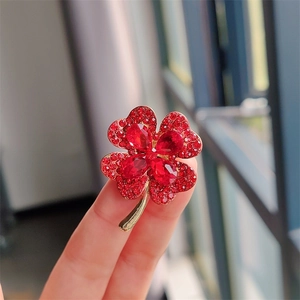 Close-up of gold clover brooch with red cat eye stone and sparkling crimson rhinestones