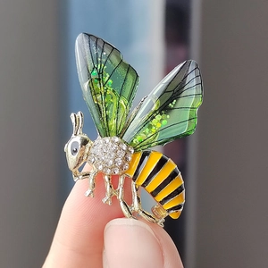 Eleganter Bienen-Anstecker mit grünen Flügeln und Goldfinish im Größenvergleich