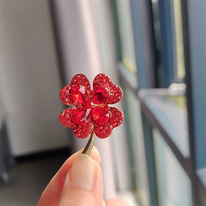 Close-up of golden four-leaf clover brooch with red crystal pavé and pear-shaped gems