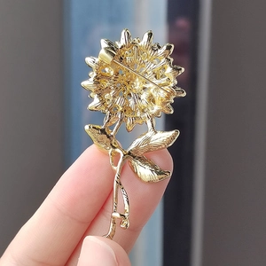 Vue arrière détaillée d'une broche tournesol dorée avec épingle de sûreté et texture métal