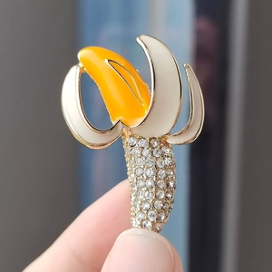 Handheld view of a creative banana brooch with yellow enamel and sparkling rhinestones