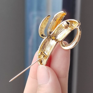 Detailed back view of a gold banana brooch showing the metal pin fastener and textured edges
