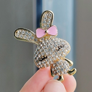 Macro shot of a gold-tone bunny brooch with sparkling white rhinestones and a pink bow