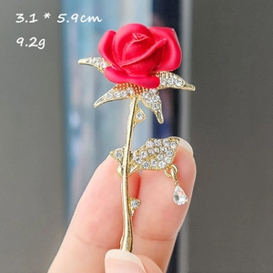 Gros plan d'une broche rose rouge avec diamants et pendentif cristal en goutte