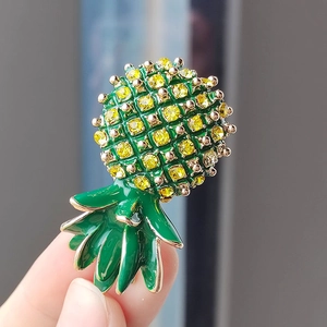 Détail de broche ananas avec cristaux jaunes et émail vert sur base en métal doré