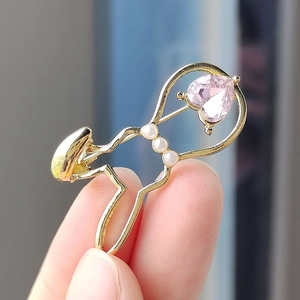 Detailed macro view of a gold ballerina brooch with a pink heart crystal and pearls