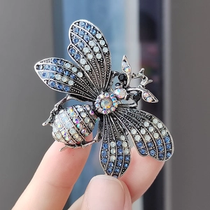 Exquisite bee brooch with blue and white crystals on silver metal base in hand