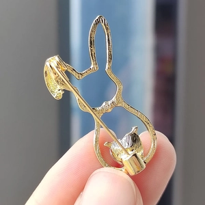 Detail view of the back of a golden rabbit brooch showing the secure pin fastener