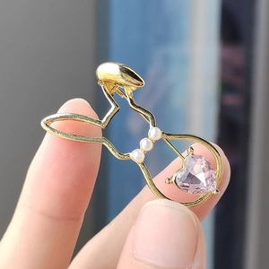Close-up of golden hollow rabbit brooch with white pearls and pink heart-shaped gem