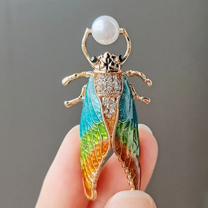 Detailed view of handmade enamel cicada brooch with pearls and sparkling crystals