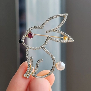 Detailed view of a silver rabbit brooch with white rhinestones and a pearl tail