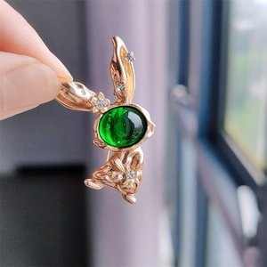 Detailed view of a gold rabbit brooch featuring a green gemstone and white rhinestones