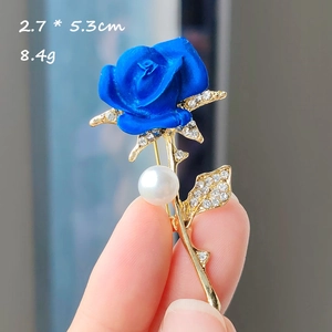 Gros plan détaillé d'une broche rose bleue avec perle blanche et strass scintillants