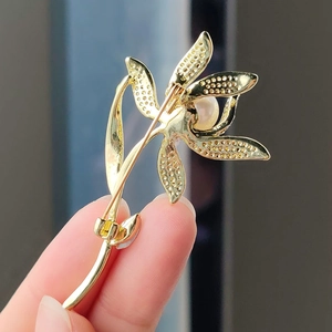 Elegante spilla a fiore dorato con petali a nido d'ape e perla, vista retro dettaglio