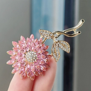 Details einer rosa Kristallblumen-Brosche mit Goldbeschichtung und weißen Akzenten