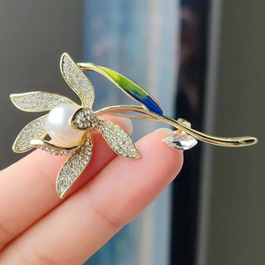 Elegante spilla a fiore dorata con perla bianca, strass brillanti e foglia di smalto verde