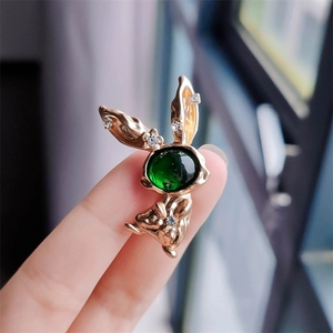Close-up of golden rabbit brooch with green gemstone and sparkling white crystals