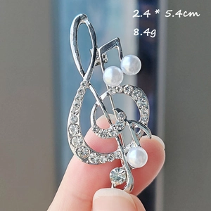 Detail of silver musical note brooch featuring sparkling rhinestones and white pearls