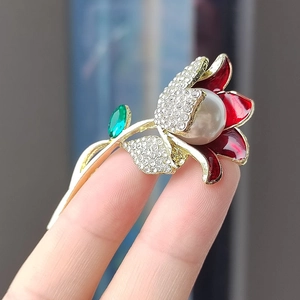 Détail d'une broche fleur 3D en émail rouge avec perle centrale et strass brillants