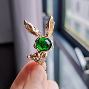 Detailed shot of a gold rabbit brooch with a green gem and sparkling small rhinestones