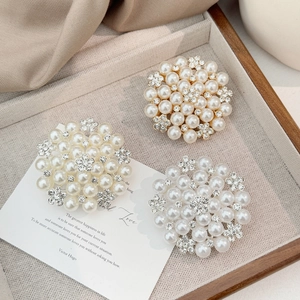 Macro shot of three high-end pearl flower brooches with sparkling rhinestone accents