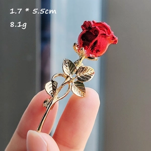 Vue détaillée d'une broche rose en émail rouge 1,7x5,5cm avec tige dorée et perle