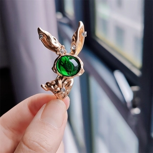 Close-up of golden bunny brooch featuring an emerald green stone and sparkling rhinestones