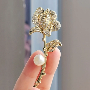 Gros plan d'une broche rose en 3D sertie de cristaux brillants et d'une perle blanche