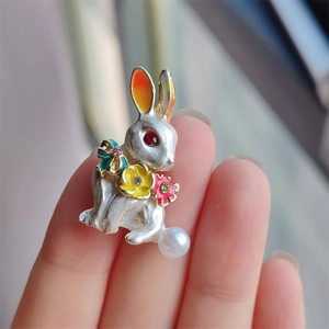 Close-up of rabbit brooch with colorful enamel flowers and a white pearl accent