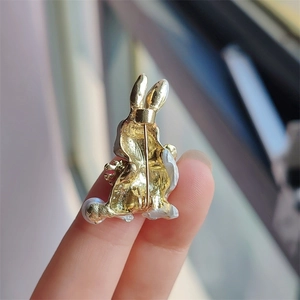 Close-up of golden rabbit brooch back with pin closure and pearl detail held by hand