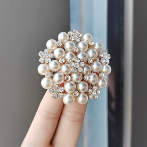 Detail shot of a round floral brooch with white pearls and sparkling crystal accents