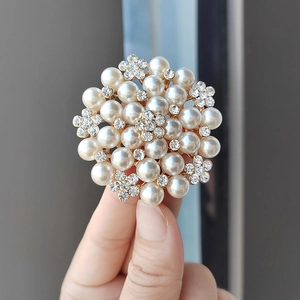 Detailed close-up of a golden flower brooch with pearls and sparkling rhinestones