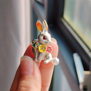 Detailed close-up of rabbit brooch with colorful enamel flowers and a pearl tail