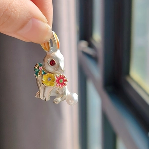 Detail of rabbit brooch with white pearl tail, enamel flowers and red gemstone eye