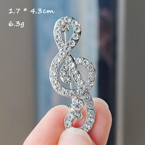 Detail of silver musical note brooch with white rhinestones and measurements 1.7x4.3cm
