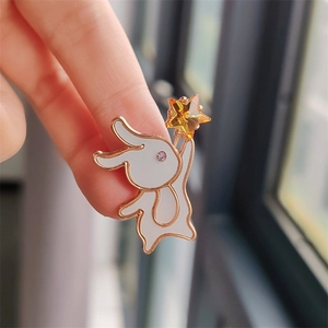 Detailed close-up of a golden bunny brooch with white enamel and a yellow star crystal