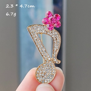 Detail view showing a musical note brooch with inlaid crystals and pink flower accents
