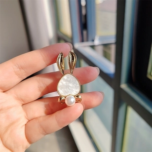 Close-up of a gold rabbit brooch with a heart-shaped body and a white pearl tail