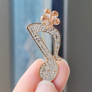 Macro view of music note brooch with gold finish, white crystals and champagne stones