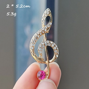 Macro shot of treble clef music note brooch with gold plating and fuchsia rhinestone