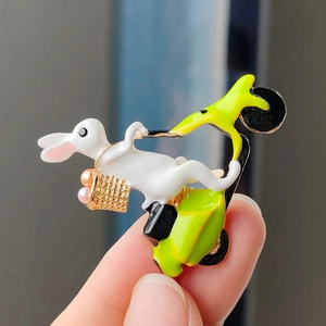 Detail of bunny riding green scooter brooch with vibrant colorful enamel work and pearls