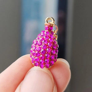 Vue macro d'un petit pendentif doré en forme de goutte serti de strass rose vif