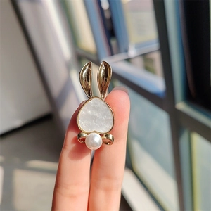 Close-up of cute rabbit brooch with heart-shaped inlay and pearl accent held by hand