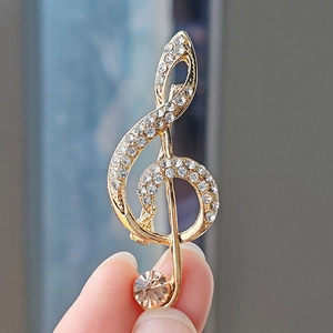 Macro shot of G-clef musical note brooch featuring sparkling crystals and champagne zircon