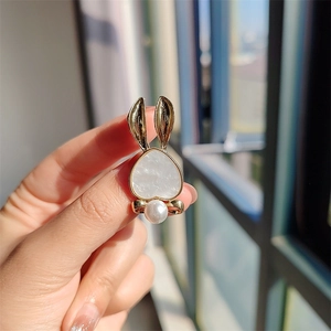 Close-up of cute golden rabbit brooch with white mother-of-pearl inlay and pearl detail