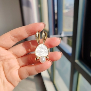 Detailed view of a gold rabbit brooch with a heart-shaped shell face and a round pearl charm