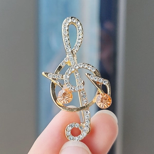 Macro shot of treble clef brooch with amber gems and inlaid rhinestones on golden metal