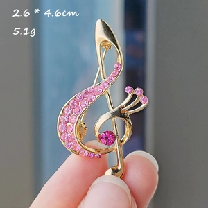 Detailed view of a gold musical note brooch with pink rhinestones, size 2.6x4.6cm