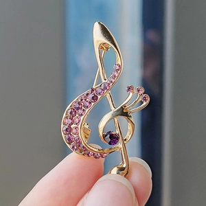 Macro detail of music note brooch with gold metal base and purple crystal rhinestones